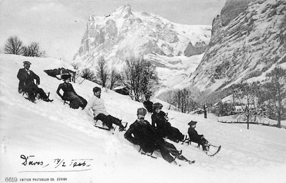 Schlittler am Fussweg oberhalb dem Tuftli, zu Salzsäulen erstarrt. Bewegen durfte man sich beim Fotografieren nicht! Im Hintergrund ein Schanzentisch, gebaut für Wagemutige, die einen Skisprung wagten. Postkarte abgesandt 1906 aus – Davos!