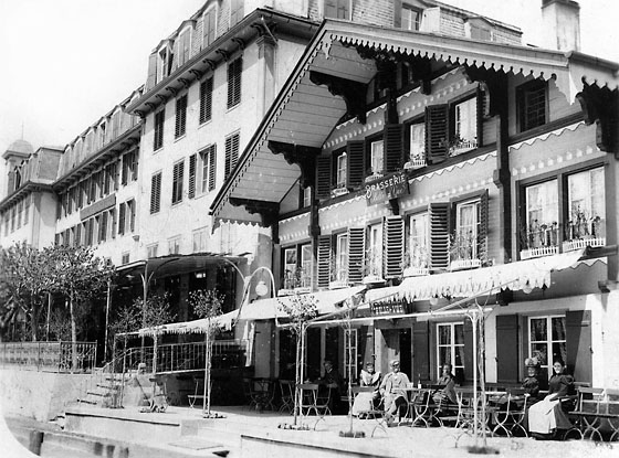 Vor der Brasserie Belle-Vue, genannt Pinte, wartet Pintenfritz Bohren auf Gäste. Hinten das riesige Grand Eiger. Im Schlechtwetterjuni 1909 kamen dort auf 200 Angestellte 9 Gäste. Das Hotel wurde 1918 abgebrochen.